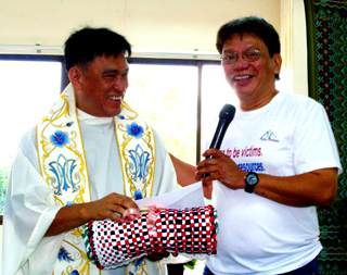 Monsignor Elmer Abacahin, SSJV, pastor of the newly-consecrated Parish of the Holy Cross in Alubijid, Misamis Oriental, smiles as he receives a token from Balay Mindanaw Foundation, Inc. founding president Charlito "Kaloy" Manlupig. (Photo by BONG D. FABE)